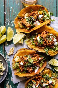 three tacos with shredded meat, lettuce and sour cream on the side