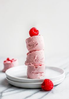 three pieces of cake on a plate with raspberry frosting and fresh raspberries