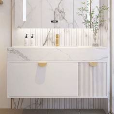 a bathroom with marble counter tops and white cabinets, along with a plant in the corner