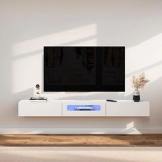 a flat screen tv sitting on top of a white entertainment center next to a potted plant