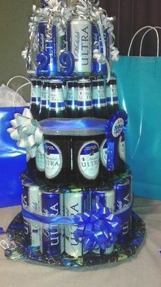 two tiered cake made out of beer cans and wrapped in blue ribbon with bows