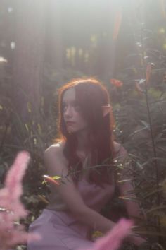 a woman is sitting in the woods with flowers