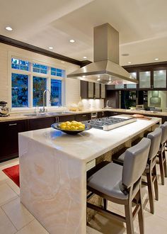 a kitchen with an island, stove and sink in the center surrounded by bar stools