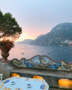 an outdoor table and chairs overlooking the ocean at sunset with boats on the water in the distance