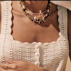 a close up of a person wearing a white shirt and necklace with beads on it