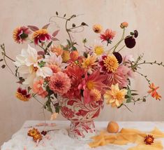 a vase filled with lots of colorful flowers on top of a white cloth covered table