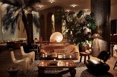 a living room filled with lots of furniture next to tall plants and potted trees