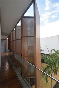 a balcony with wood and glass railings next to palm trees on the other side