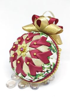 a christmas ornament with gold and red ribbon on it's top, surrounded by pearls