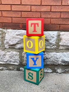 a stack of blocks with letters and numbers on them sitting in front of a brick wall