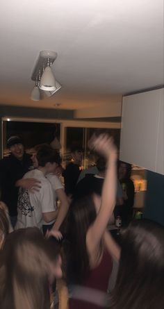 a group of people standing around each other in a room with one person holding his arms up