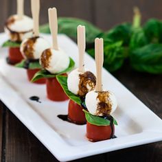 small appetizers with toothpicks and tomatoes on a white plate