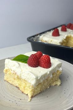 a piece of cake with white frosting and raspberries on top