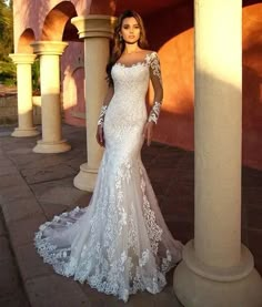 a woman in a white wedding dress standing next to pillars and wearing an off the shoulder gown