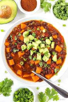 a white bowl filled with beans, avocado and black bean chili next to other ingredients