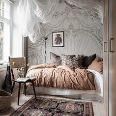 a bedroom with a bed, rugs and pictures on the wall above it in front of a window