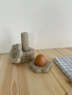 an egg sitting on top of a wooden table next to two rolls of toilet paper