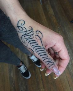 a person with a tattoo on their arm holding the word summer written in cursive writing