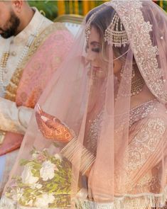 the bride is looking down at her wedding dress and veil while she waits to be married