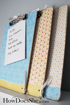 three binders are attached to a wall with a notepad on it and a clipboard in front of them