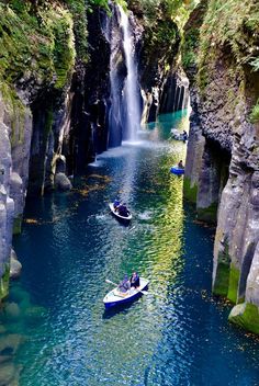 two boats in the water near a waterfall