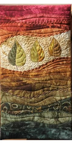 a quilted wall hanging with leaves on it