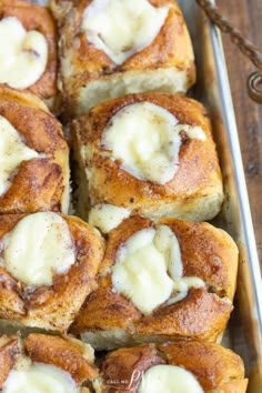 cinnamon rolls with cream cheese on top in a baking pan, ready to be eaten