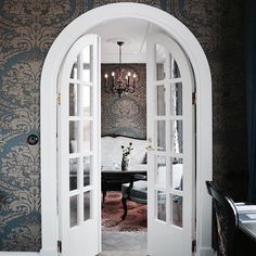 an open door leading to a living room with a chandelier hanging from the ceiling