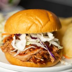 a pulled pork sandwich with coleslaw and slaw on a plate next to potato wedges