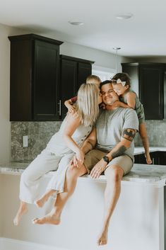 a man and two women sitting on top of a kitchen counter with their child in the air