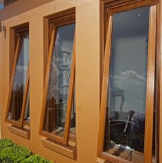 three windows with wooden frames on the side of a building