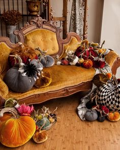 a couch covered in lots of pumpkins and other decorative items on top of a wooden floor