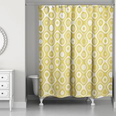 a yellow shower curtain with white circles on it in a bathroom next to a dresser and mirror