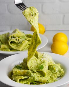 a fork lifting up some food from a white plate with lemons in the background