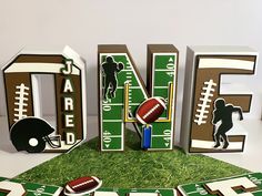 the letters are made out of wood and decorated with footballs, helmets, and other sports related items