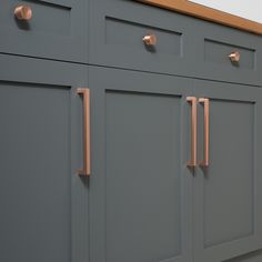 a kitchen with gray cabinets and copper pulls on the doors, along with white walls