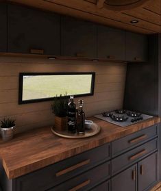 the kitchen counter is made from wood and has two bottles on it, along with a potted plant