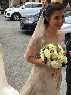 the bride is walking down the street with her bouquet in hand and she is smiling