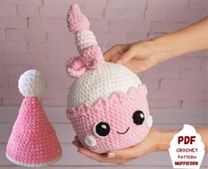 a crocheted pink and white stuffed animal next to a hand holding a knitted hat