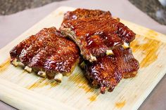 two pieces of ribs sitting on top of a cutting board