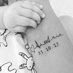 a close up of a person holding a baby's arm with a tattoo on it