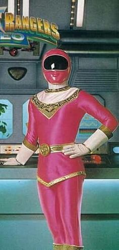 a man in a pink suit and helmet standing next to a counter with food on it