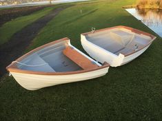 two small boats sitting on the grass near water