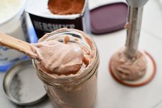 a jar filled with chocolate frosting next to two spoons