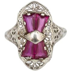 an antique style ring with pink stones and filigrees on the sides, set in