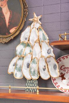 a christmas tree made out of seashells sits on a shelf next to plates