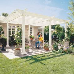 two people sitting on a patio under a white pergoline over an outdoor dining area