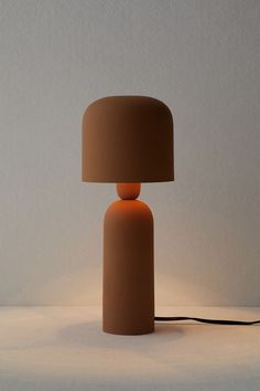 an orange lamp sitting on top of a table next to a white wall and floor