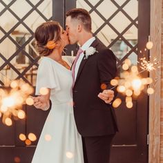 a bride and groom kissing in front of sparklers