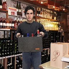 a man standing in front of a wine rack holding a box with bottles on it